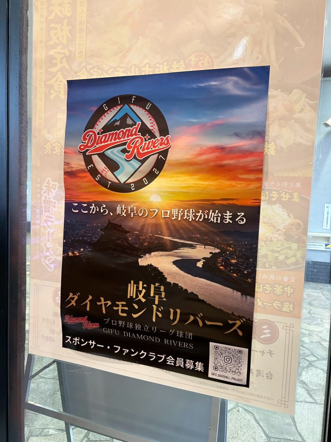 夕焼けに染まる川と街並みに球団ロゴを重ねた球団ポスター。「ここから、岐阜のプロ野球が始まる」の文字